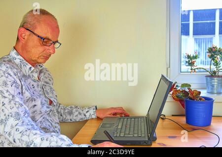 Mature man using a graphic pad and notebook in the home office Stock Photo