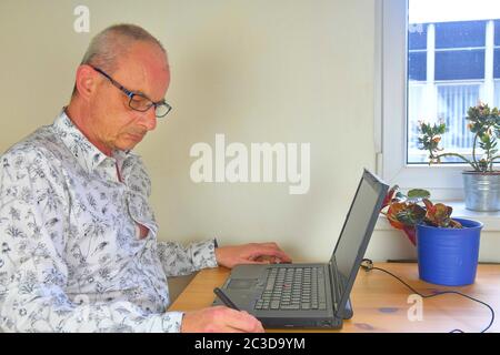 Mature man in home office working with graphics tablet and notebook Stock Photo
