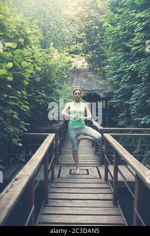 Woman meditating on wooden bridge in forest Stock Photo