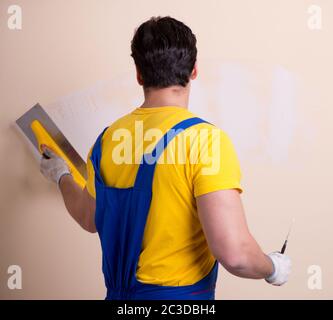 Young contractor employee applying plaster on wall Stock Photo