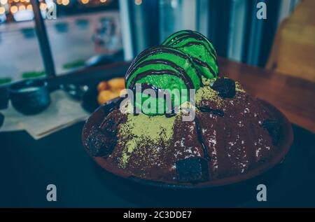 view from above on green tea bingsu decorated with chocolate and matcha powder and chocolate cake pieces Stock Photo
