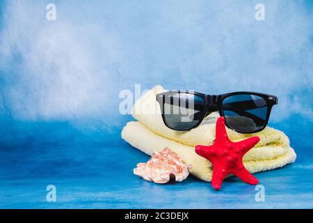 Sunglasses, towel, seashell and starfish on the blue background Stock Photo