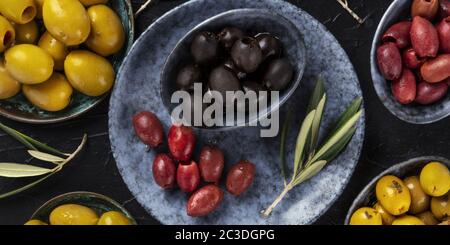 Olives overhead panorama. An assortment of green, black and red olives, shot from the top on a dark table Stock Photo