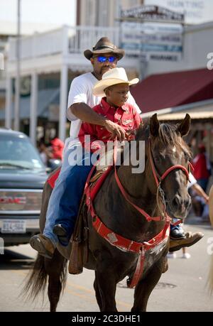 Bastrop, Texas, USA. 21st June, 2008. Bastrop, TX June 21, 2008: African-American cowboy and his son riding in a Juneteenth celebration in the historically African-American suburb of Bastrop, outside Austin. Juneteenth celebrates the day, June 19, 1865 when Union soldiers landed in Galveston, TX announcing the end of slavery and the Civil War. Credit: Bob Daemmrich/ZUMA Wire/Alamy Live News Stock Photo