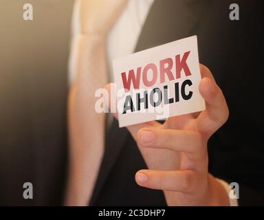 Workaholic word on a card in hand of businessman. Devoted to business or career concept Stock Photo