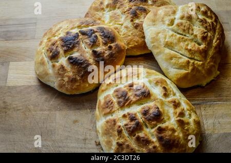 Little italian focaccia breads homemade and freshly cooked on a wooden table close up. The focaccia is a traditional italian oven baked flat bread. Stock Photo