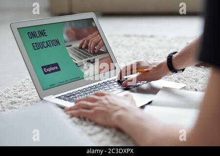 Close-up of unrecognizable student using laptop while taking online course during quarantine Stock Photo