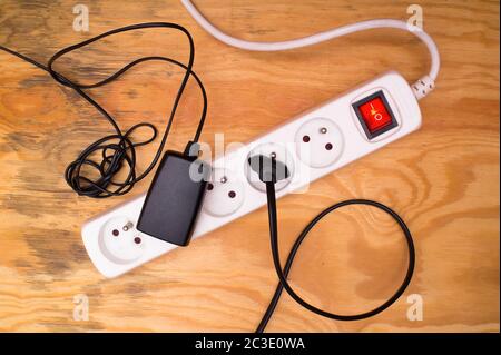 Flat lay - extension cord and plugged cables and devices on wooden floor Stock Photo