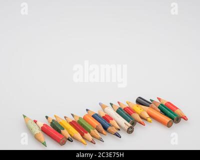 The remains of old colored pencils. Little pencils on a white background. Stationery. Stock Photo
