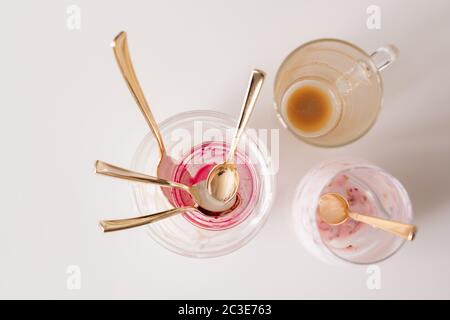 Group of empty unwashed glasses and teaspoons on kitchen table after breakfast consisting of coffee and yoghurt with homemade jam Stock Photo