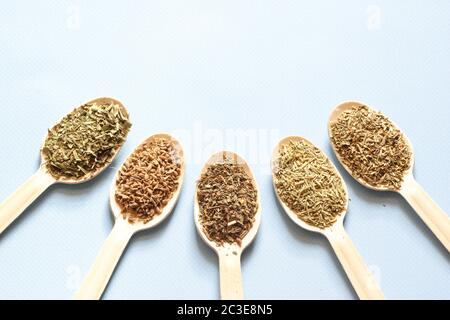 Wooden wooden spoons with spices are laid out in a semicircle. Collection of spices from herbs on the blue background Stock Photo
