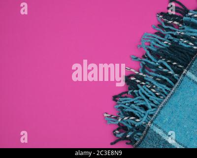 Warm turquoise plaid on a bright pink background. A cozy piece of interior. View from above. Stock Photo