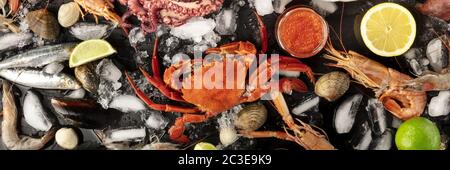 Crab with fish, shrimps, and caviar, overhead seafood panorama on a dark background Stock Photo