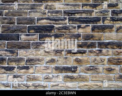 a full frame image of a large old dark stone wall made of large sandstone blocks Stock Photo