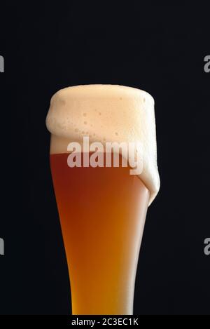 Cold white beer in a long classic glass with foam. German traditional drink, the yeast beer. Glass of white beer, bavarian beverage. Stock Photo