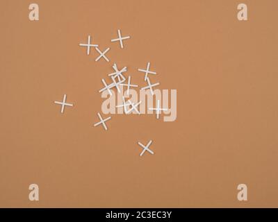 Crosses for tiled work. Tiler accessories. The view from the top. Brown background. Stock Photo