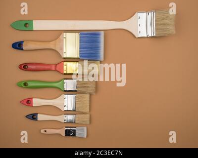 Different brushes for painting on a beige background. The view from the top. Colored brush. The concept of repair. Stock Photo