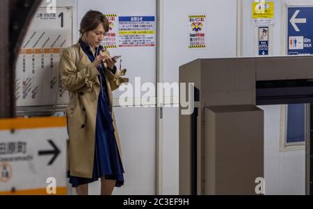 Japanese woman in an overcoat waiting for a subway train, Asakusa, Tokyo, Japan Stock Photo