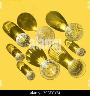 Glasses with clear water stand on a yellow background, top view. Beautiful creative still life is flooded with light with hard shadows and glare from Stock Photo