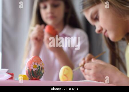 Children paint Easter eggs, focus on the egg in front of them Stock Photo