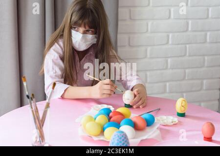 Sad sick quarantined girl paints Easter eggs Stock Photo
