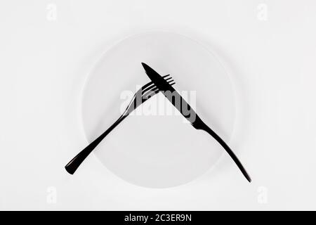 Cutlery language. Plate with fork and knife, top view. Stock Photo