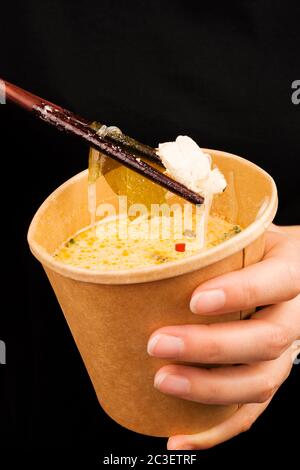 Woman eating tom yam soup in eco cup. Stock Photo