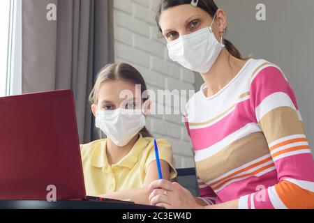Mom and daughter in medical masks quarantined study online Stock Photo