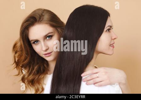 Two beautiful multicultural young women over beige background Stock Photo