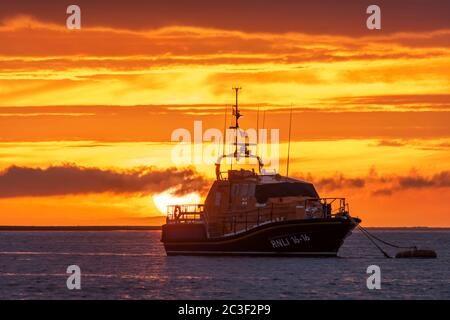 Appledore, North Devon, England. Friday 19th June 2020. UK Weather. After a day of sunshine and showers in North Devon, the sun goes down behind RNLB 'Mollie Hunt', the RNLI's Tamar-Class all weather lifeboat at her mooring on the River Torridge in Appledore. Credit: Terry Mathews/Alamy Live News Stock Photo