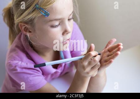 Girl (7) writes on her hand, Kiel, Schleswig-Holstein, Germany Stock Photo