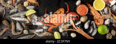 Seafood. Crab, mussels, shrimps, clams on ice, shot from the top on a black background Stock Photo