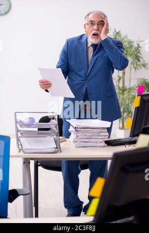Old male employee and too much work in the office Stock Photo