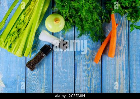 Ingredients for soup: herbs , salt, pepper, onion and carrot on blue wooden background. Stock Photo