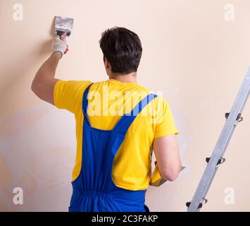 Young contractor employee applying plaster on wall Stock Photo