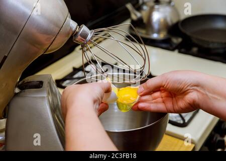 Woman separates egg whites from yolk in mixer bowl. Cooking biscuit. Stock Photo