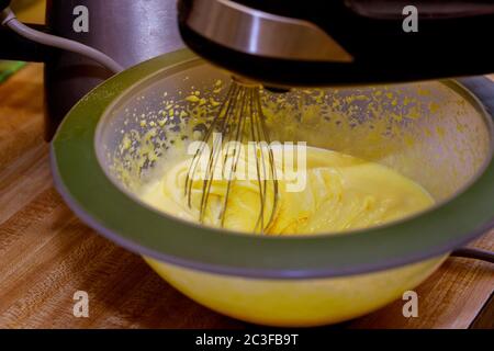 Whipping egg yolks and sugar in bowl with electric mixer. Stock Photo