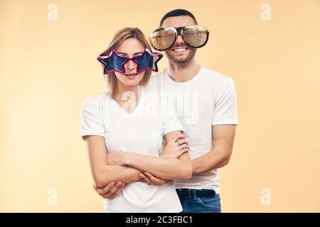 Young happy couple in funny party glasses on beige background Stock Photo