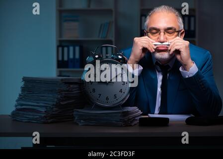 Old male employee working late in the office Stock Photo