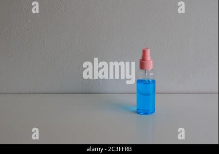 Blue color hand sanitizer placed on wooden table against cement wall, people have to clean their hands frequenly due to coronavirus pandemic Stock Photo