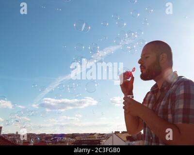 Man blowing soap bubbles from his balcony. Exit restriction quarantine due to coronavirus, home offi Stock Photo