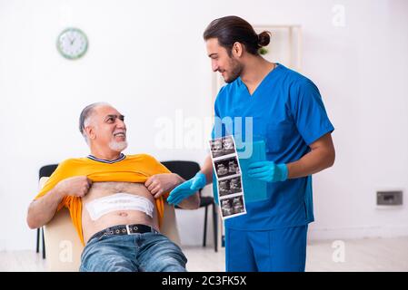 Old man visiting young male doctor Stock Photo