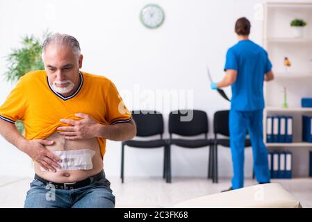 Old man visiting young male doctor Stock Photo