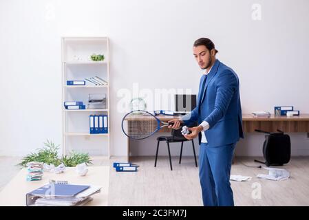 Young male employee playing tennis in the office Stock Photo