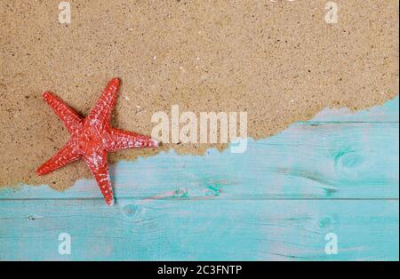 Red starfish on sea sand on blue wooden background. Summer or travel concept. Stock Photo