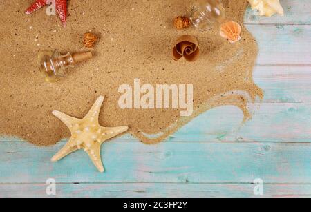 Starfish with seashells on sea sand on blue wooden background. Papyrus from the glass bottle with cork. Stock Photo