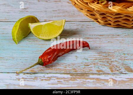 Red chili pepper with slices of lime on blue wooden table. Stock Photo