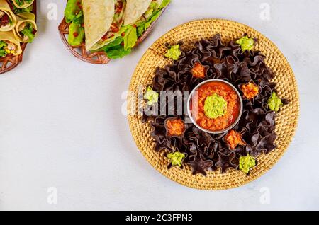 Blue corn tortilla chips with salsa and guacamole on white background. Hispanic food. Stock Photo
