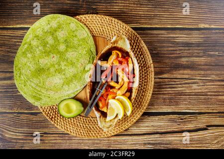 Spinach tortillas with stir fry chicken and vegetable on wood background. Stock Photo