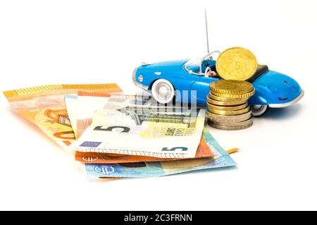 Stacks of giant silver coins and banknotes next to a new blue hoodable car Stock Photo